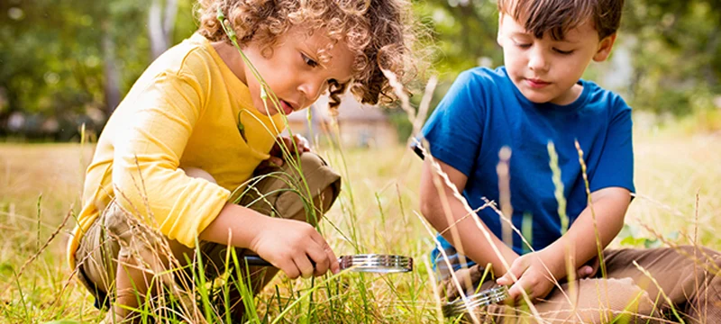 Two boys looking at ants in the grass