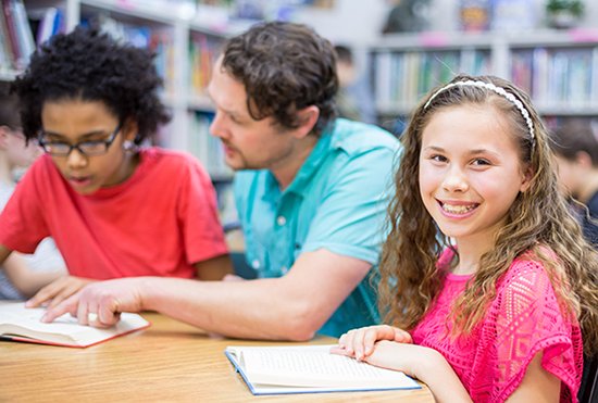 Two students and a teacher, one of the students smiling at the camera.