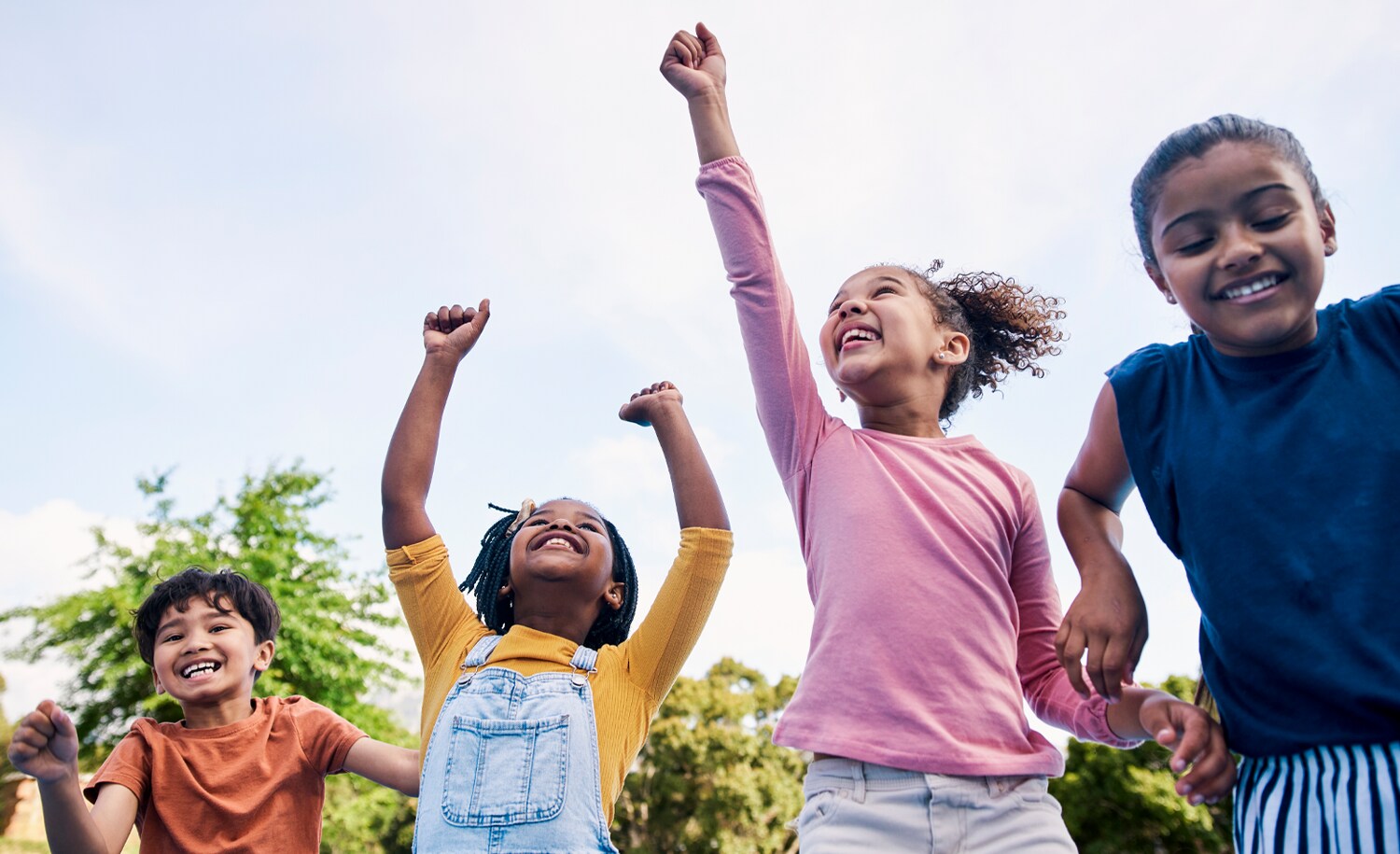 Several children raising their arms up in excitement.