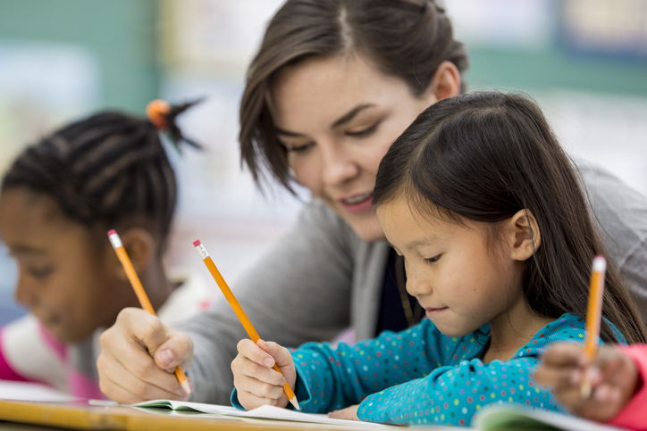 student reading and writing with teacher