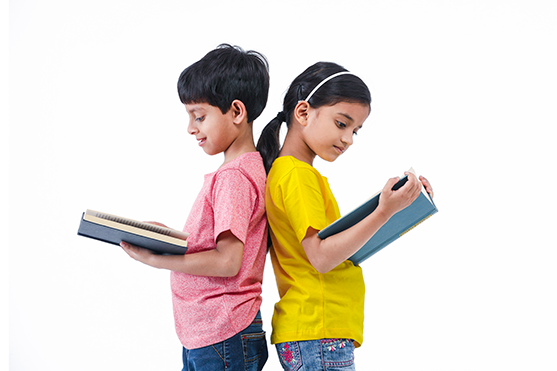 Two children standing back to back reading books.