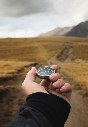 Someone holding a compass in a mountain landscape.