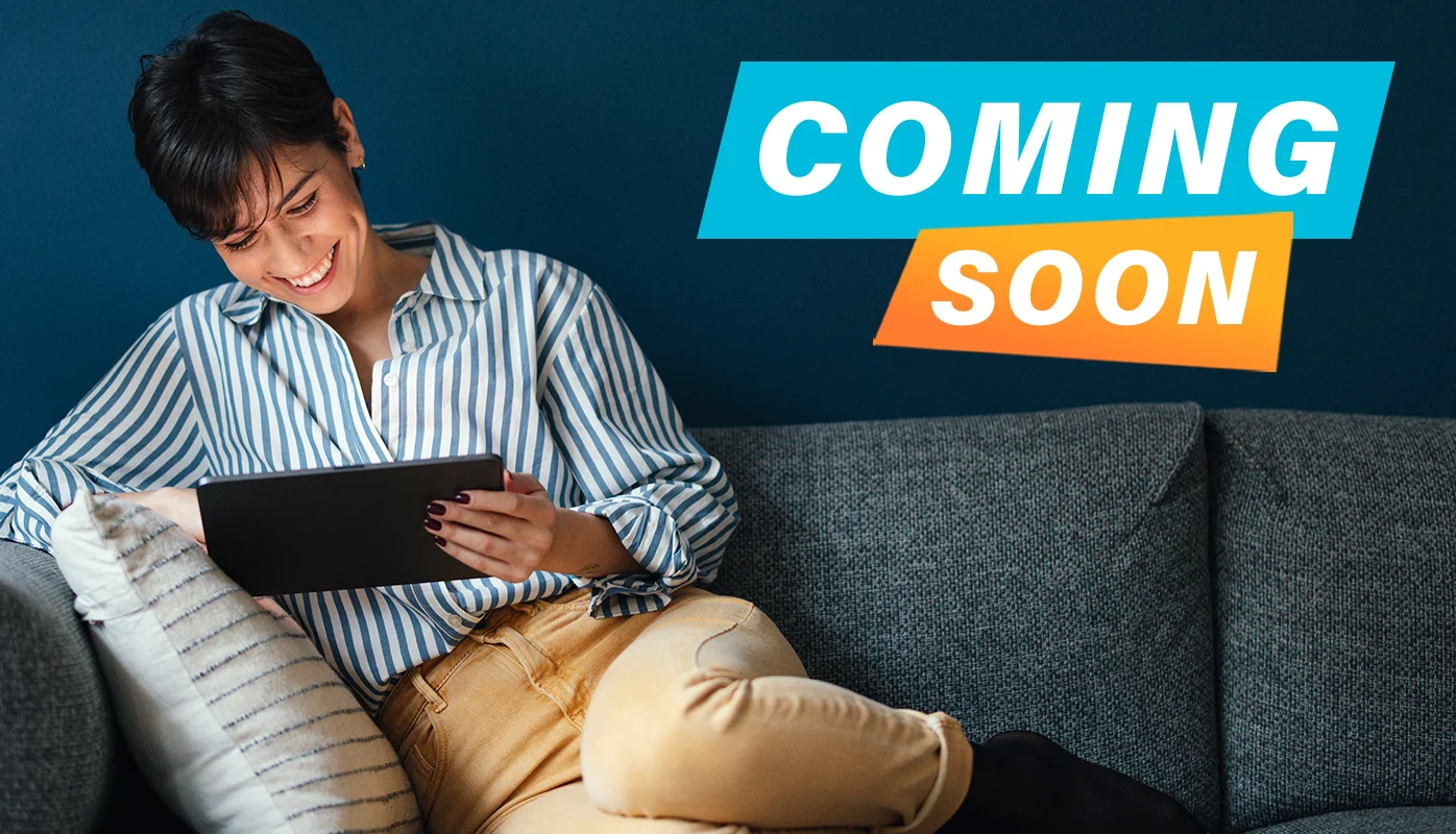 A woman in a striped shirt is using a tablet and sitting on a sofa.